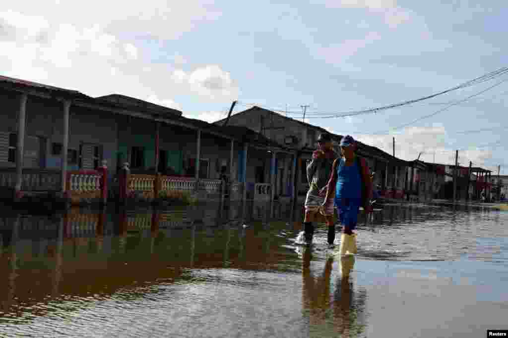 Mujeres caminan por una calle inundada, en Batabanó, Cuba, por los efectos del huracán Milton. REUTERS/Norlys Perez